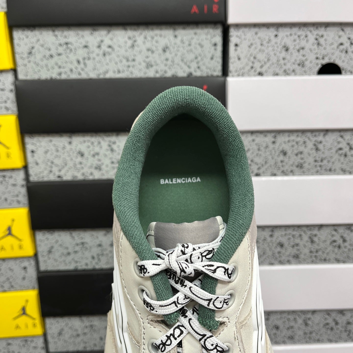 White Balenciaga sneaker heel with green fabric collar and lace-up opening.