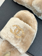 Beige plush slide sandal with gold chain-like logo emblem on strap