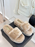 Beige faux fur slip-on slides with gold logo appliques on top