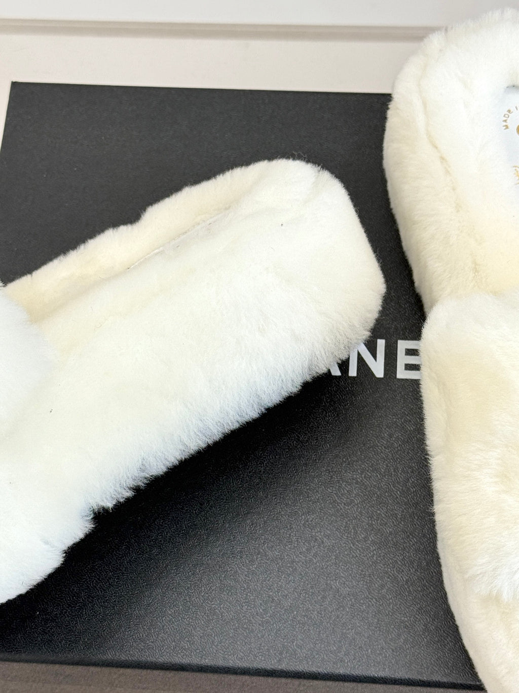 White faux-fur slide sandal close-up on black display box