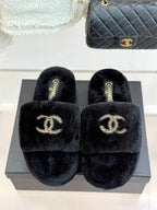 Black fuzzy slide sandals featuring a gold-tone CHANEL logo on the front
