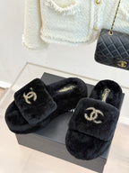 Pair of black faux-fur CHANEL slides on a box, with jeweled-look logo details