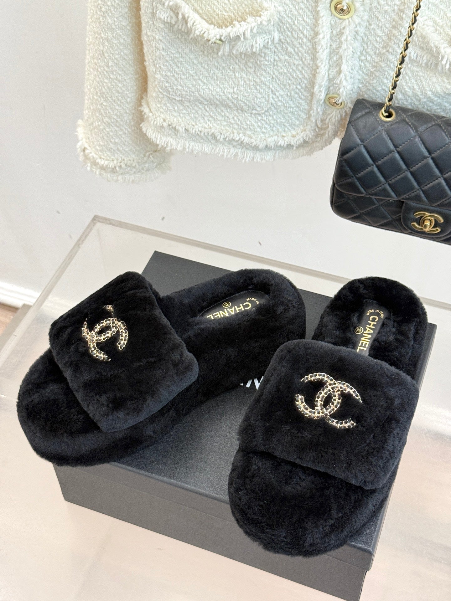 Pair of black faux-fur CHANEL slides on a box, with jeweled-look logo details