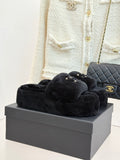 Black faux-fur slide sandals with gold-tone CHANEL logo on the front strap