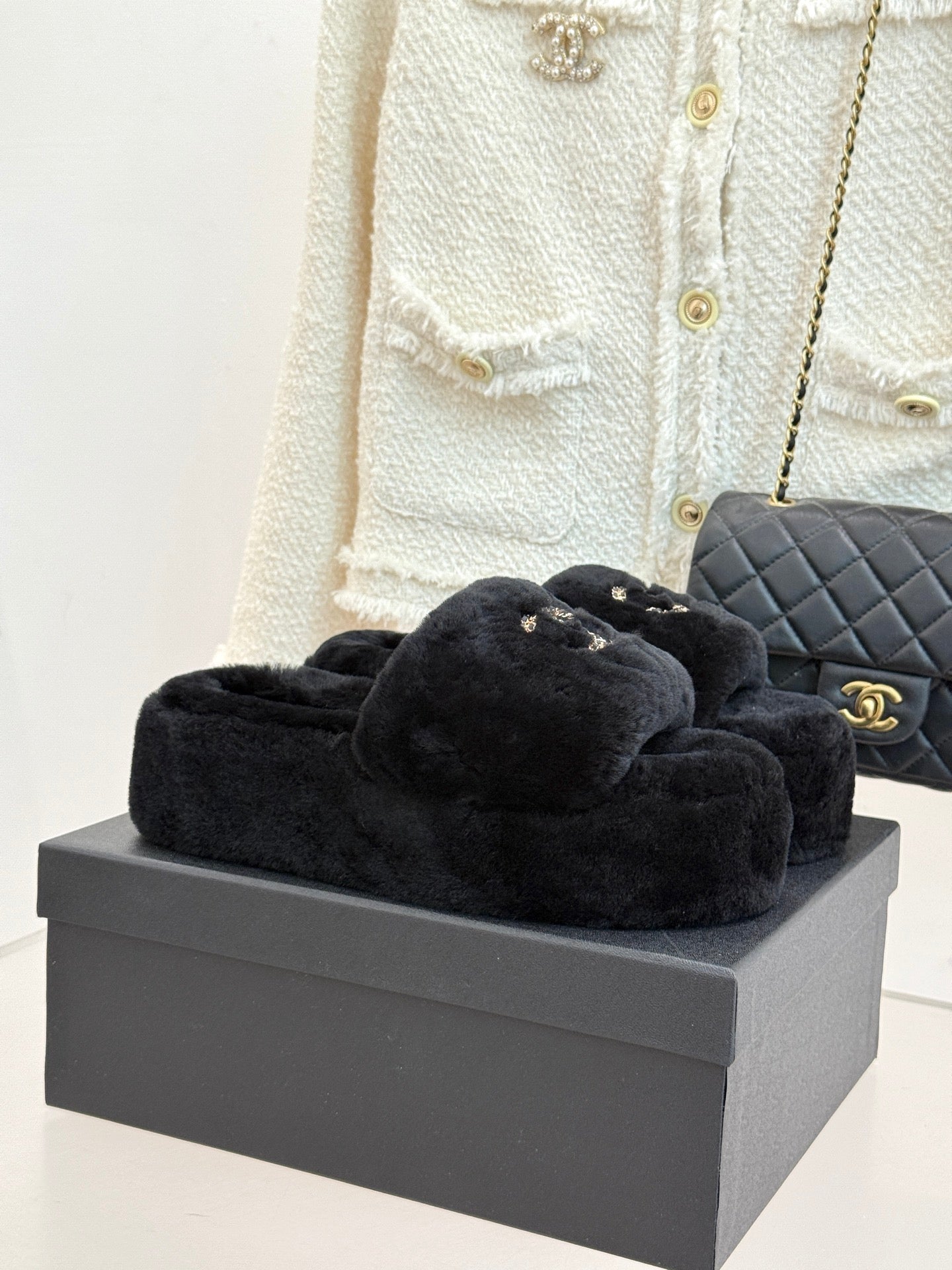 Black faux-fur slide sandals with gold-tone CHANEL logo on the front strap