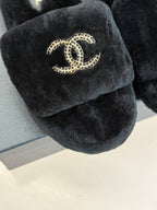 Close-up of black faux-fur CHANEL slide sandal with gold-tone logo on the strap
