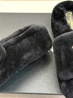 Black faux-fur slide sandals showing thick straps and textured front platform