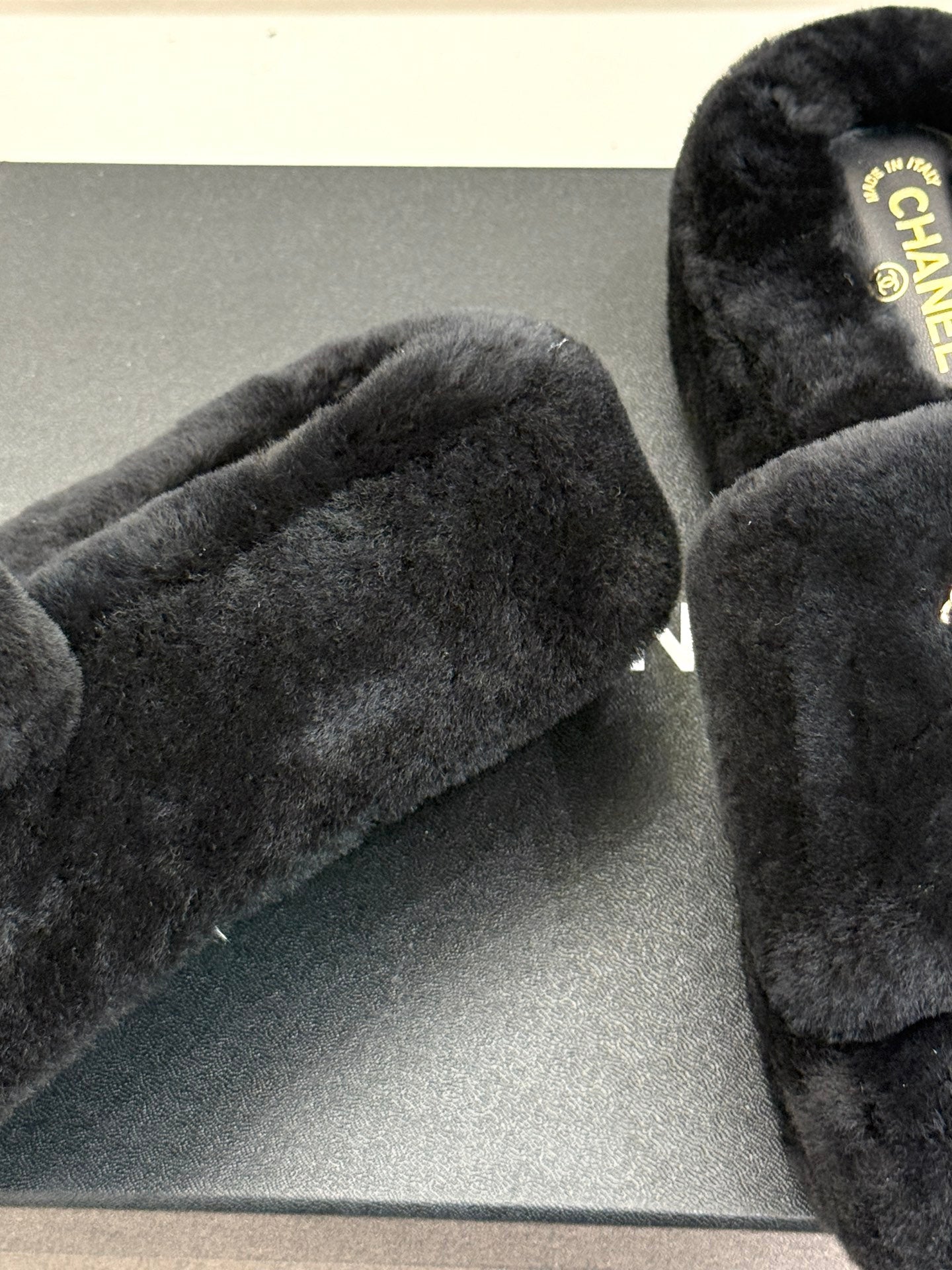 Black faux-fur slide sandals showing thick straps and textured front platform