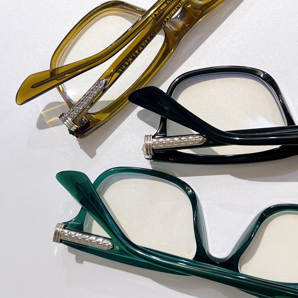 Set of clear-lens eyeglasses in gold, black, and green with metal hinges