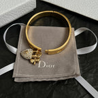 Gold-tone cuff bracelet with pavé heart charm, on gray fabric pouch