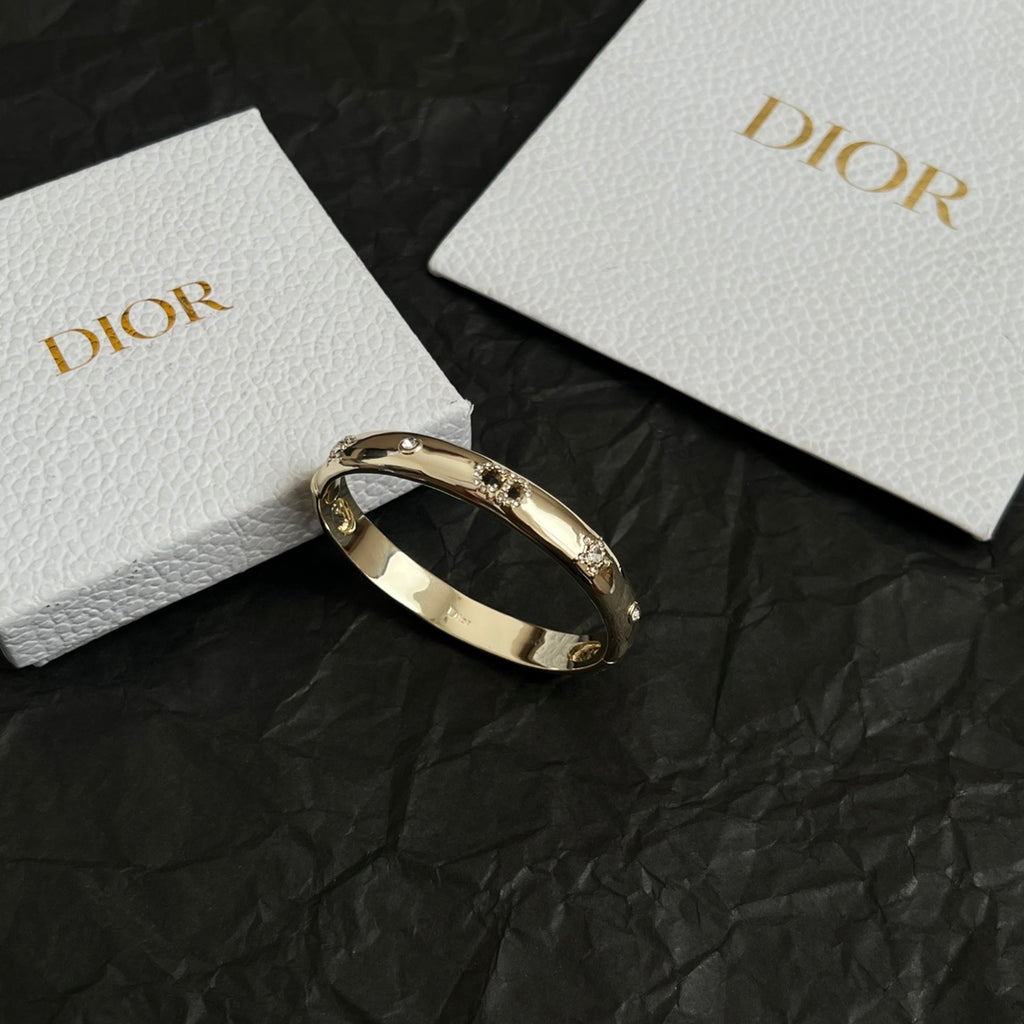 Gold-tone Dior bangle bracelet with clear stones, open hinged cuff.