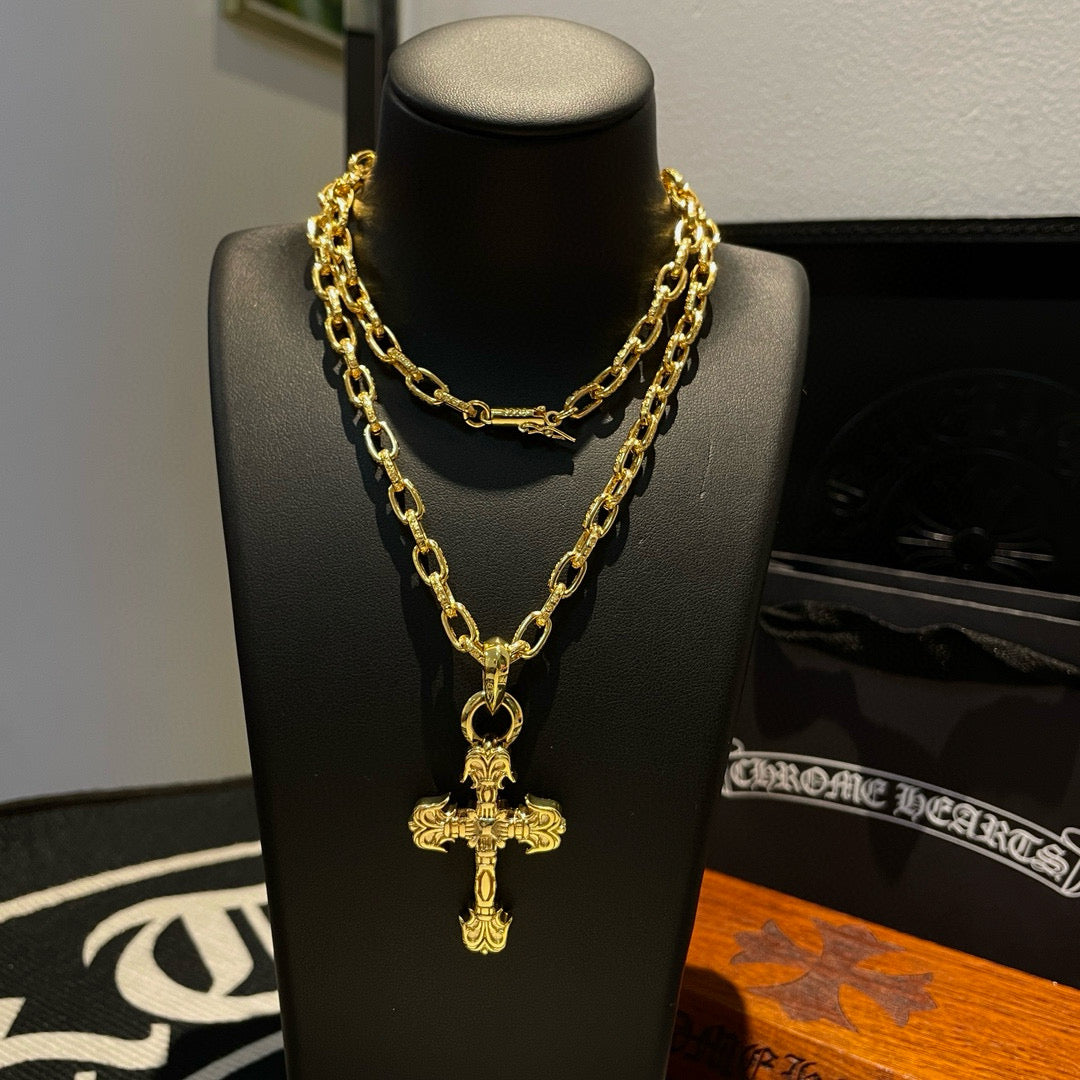 Gold-tone cross pendant necklace with layered chain on a display bust
