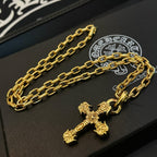 Gold-tone cross pendant necklace laid flat on a black jewelry display tray