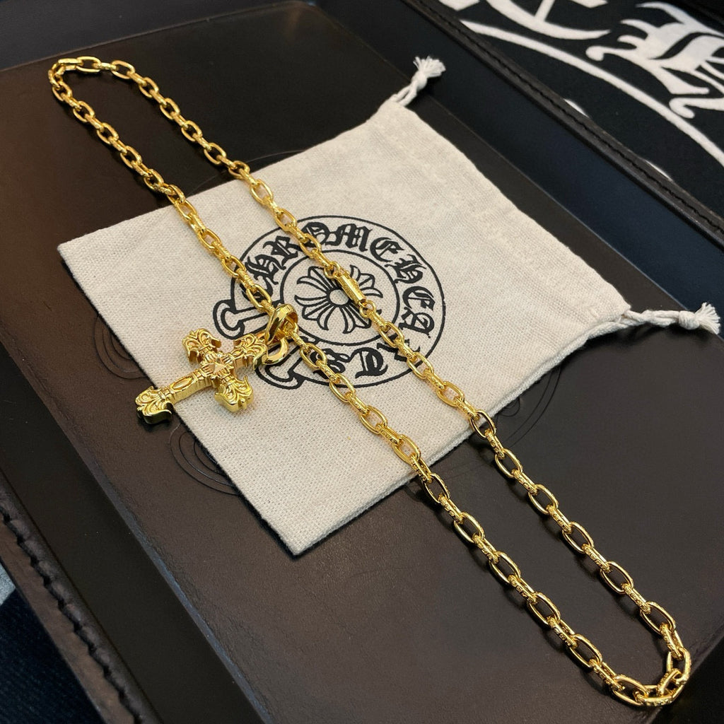 Gold-tone cross pendant necklace resting on a light pouch inside a box
