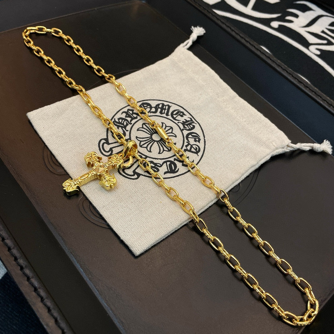 Gold-tone cross pendant necklace resting on a light pouch inside a box
