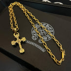 Gold-tone cross pendant necklace with multiple chain layers on a black box