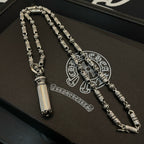 Beaded metal necklace laid on box, with engraved medallion charm and pendant