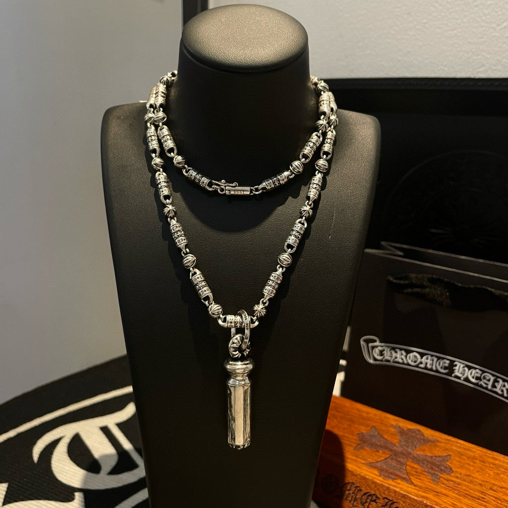 Beaded metal necklace on display bust, layered chain with cylindrical pendant