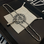 Beaded metal necklace with cylindrical pendant and clasp, on jewelry box