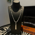 Beaded metal necklace on display bust, with tall cylindrical pendant