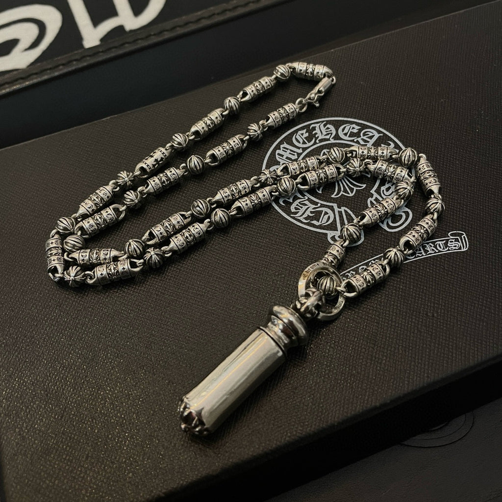 Beaded metal necklace on jewelry box, with cylindrical pendant and small clasp