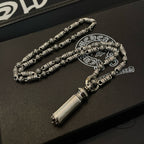 Beaded metal necklace on jewelry box, with cylindrical pendant and small clasp