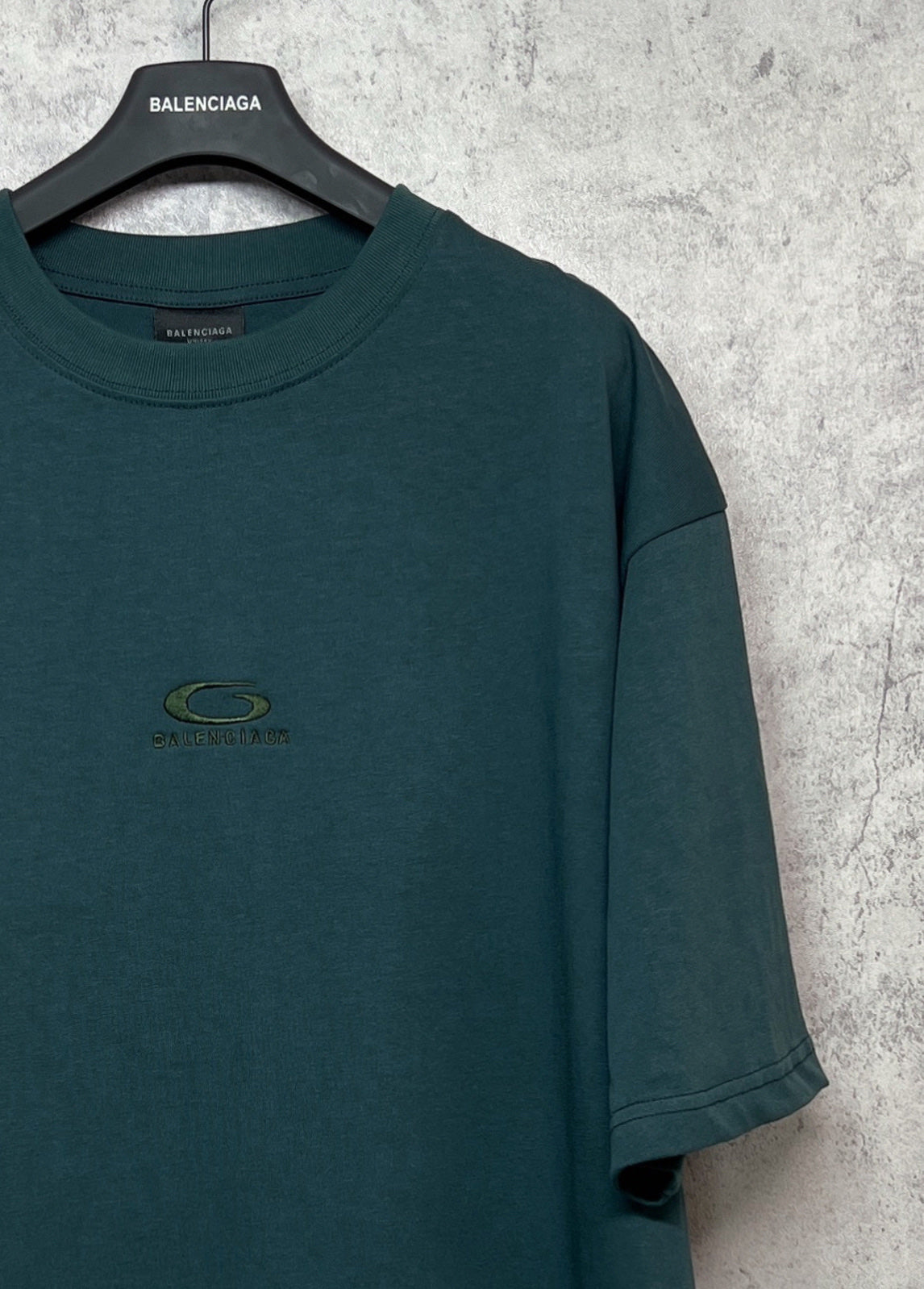 Teal T-shirt chest area with small emblem logo and short sleeves