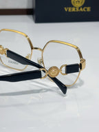 Versace eyeglasses close-up: gold-tone round frame with navy tips and Medusa logo