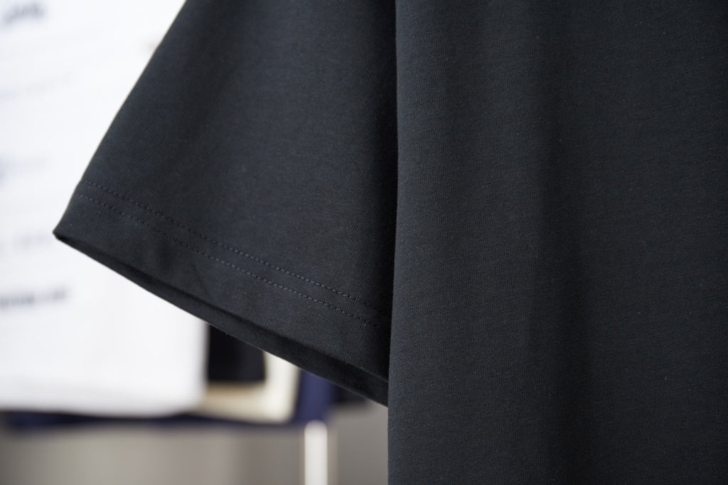 Black T-shirt sleeve and hem detail with clean stitched edges