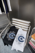 Folded black and white T-shirts with blue circular emblem on front