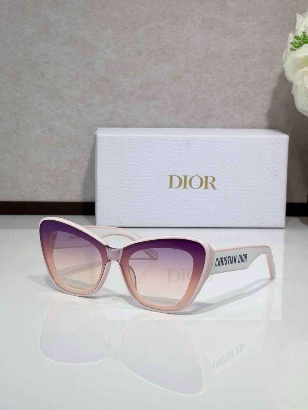 Dior sunglasses with light pink frames and purple-tinted gradient lenses