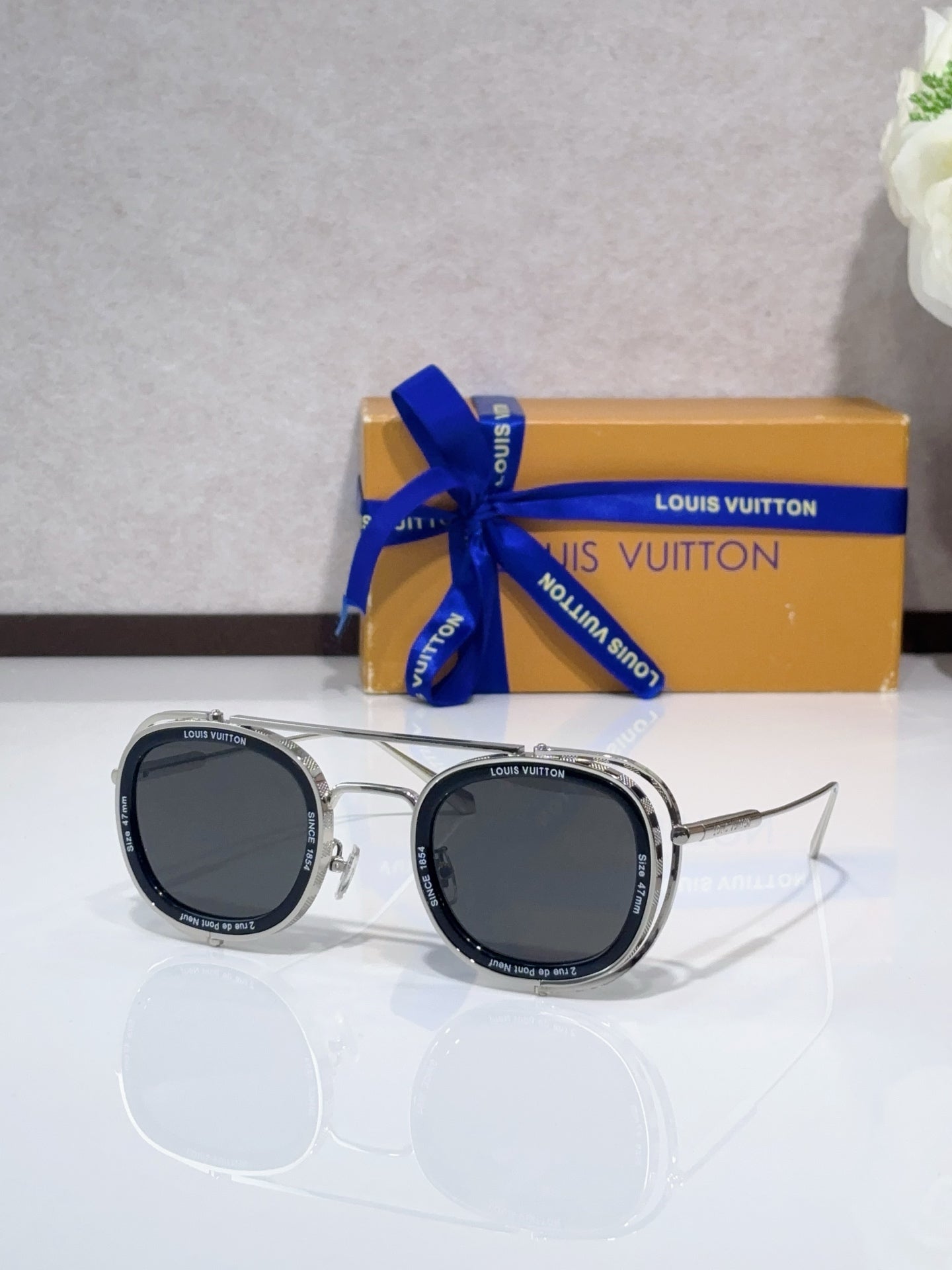 Louis Vuitton round sunglasses with silver-tone frame and dark lenses, side view.
