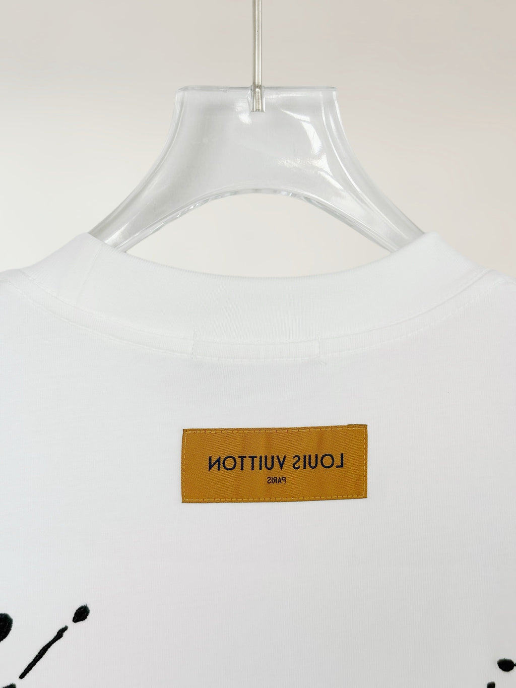 White Louis Vuitton T-shirt close-up of yellow brand label on the chest