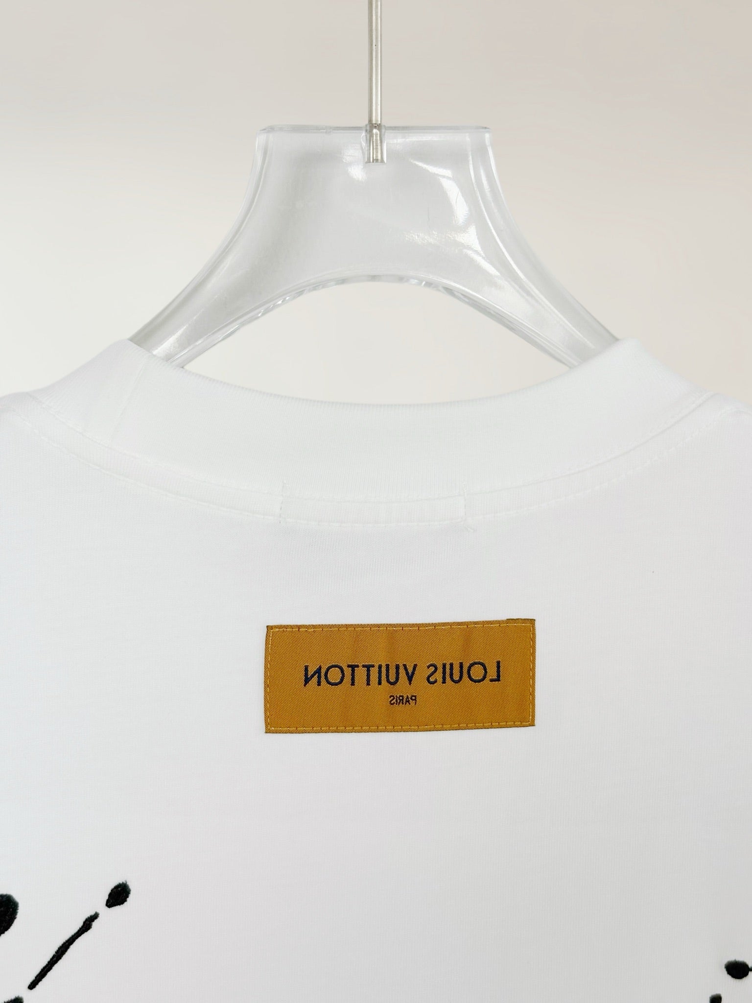 White Louis Vuitton T-shirt close-up of yellow brand label on the chest
