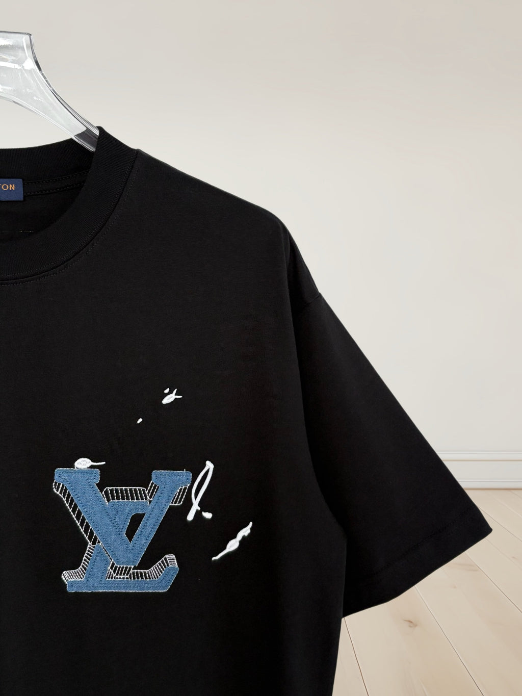 Black T-shirt sleeve with blue and white embroidered graphic logo