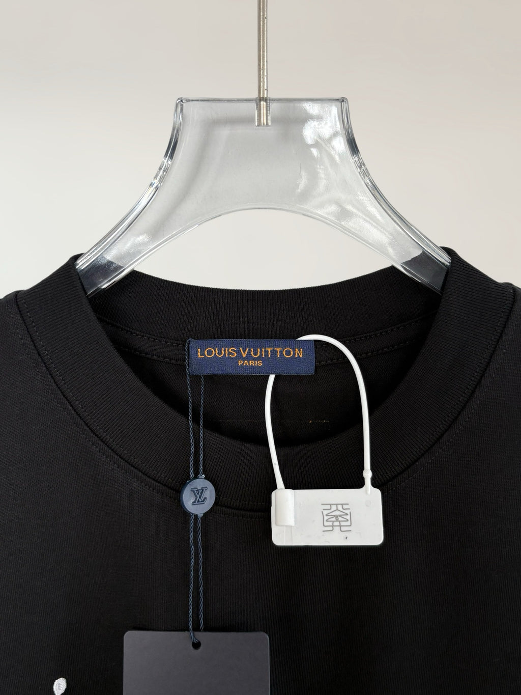 Black T-shirt with round neck, collar tag, and small hanging padlock charm