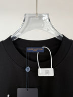 Black T-shirt with round neck, collar tag, and small hanging padlock charm