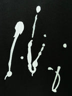 Black T-shirt detail with white splash-like graphics on black fabric