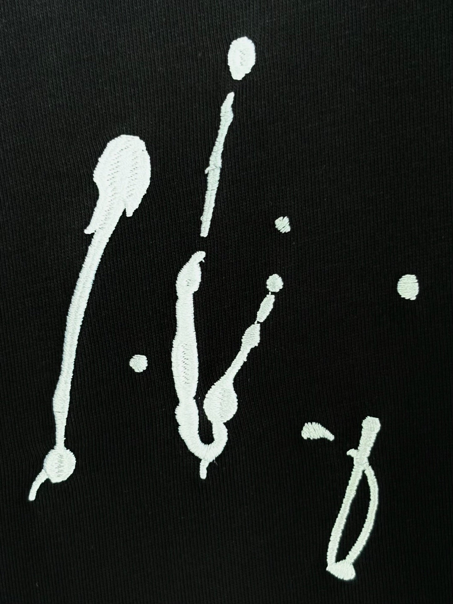 Black T-shirt detail with white splash-like graphics on black fabric
