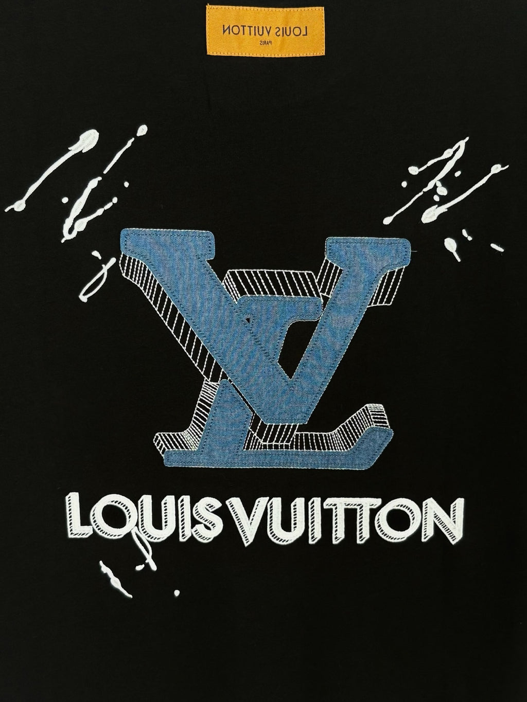 Black T-shirt with blue crest and white LouisVuitton wordmark, splash marks