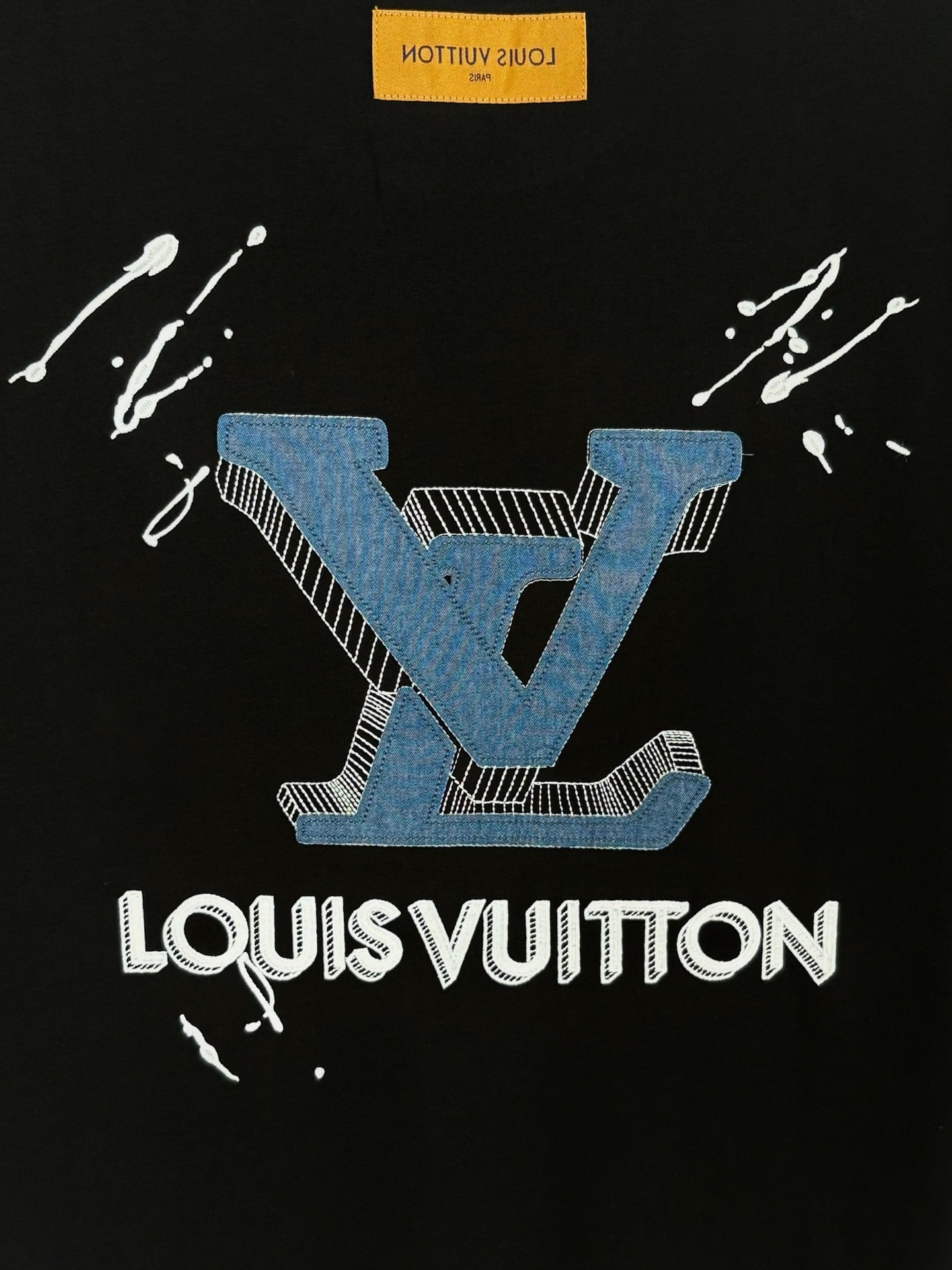 Black T-shirt with blue crest and white LouisVuitton wordmark, splash marks