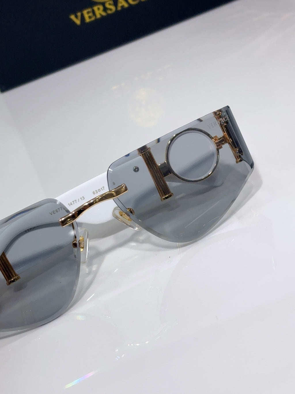 Sunglasses frame close-up with gold-tone metal hinge detail and gray tinted lens