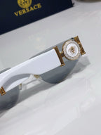 Sunglasses frame close-up with gold medallion detail and gray tinted lens