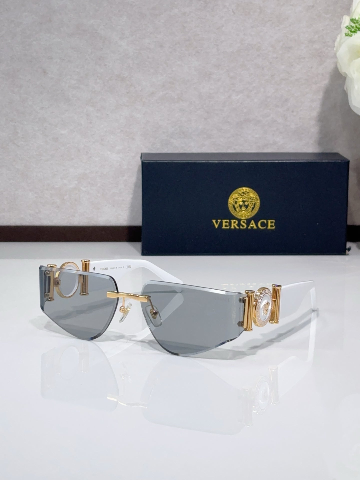 Shield sunglasses with pale frame, gold-tone accents, and gray tinted lenses