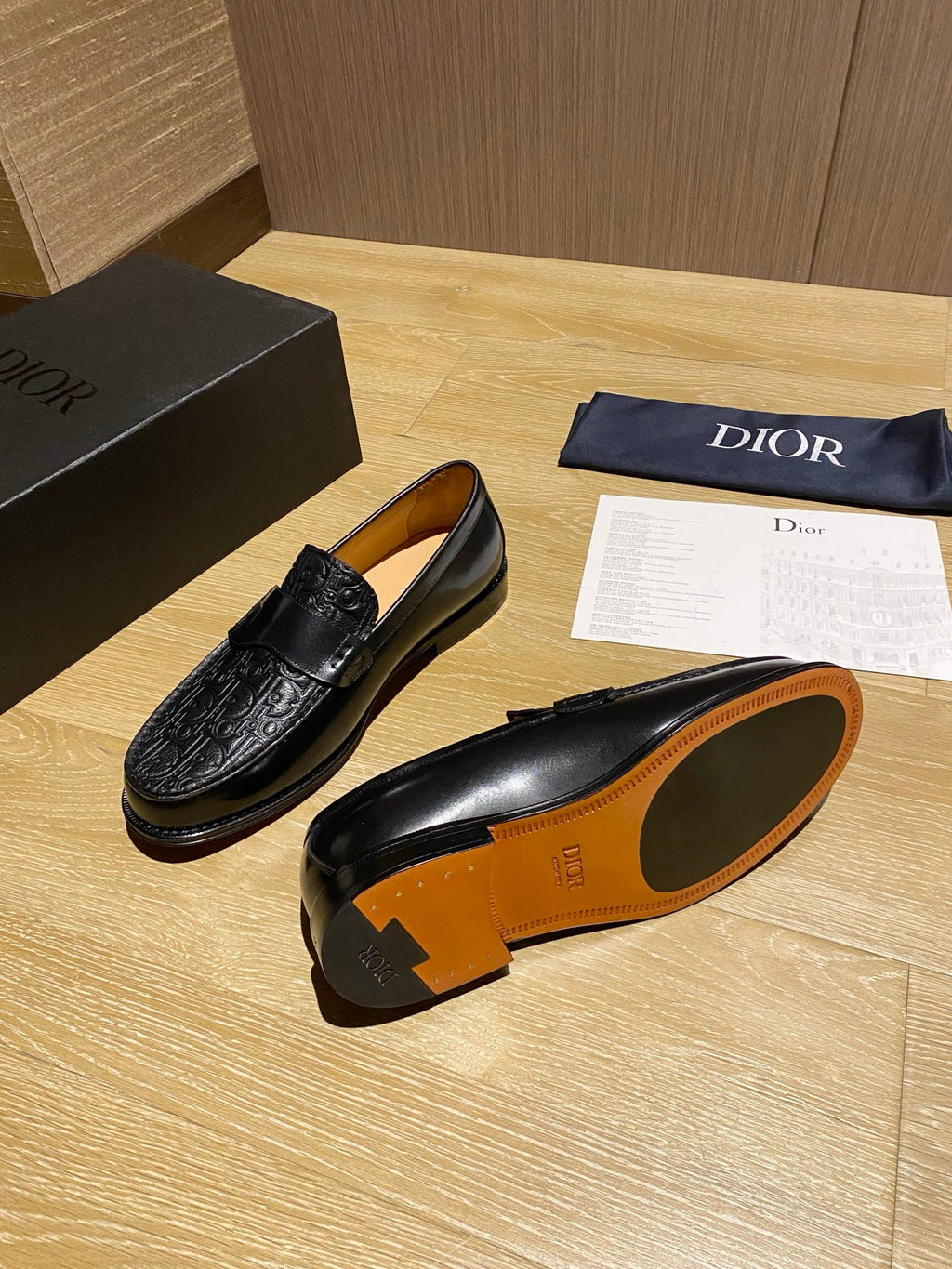 Black leather loafers with embossed front and orange-tan underside sole