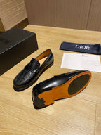 Black leather loafers with embossed front and orange-tan underside sole