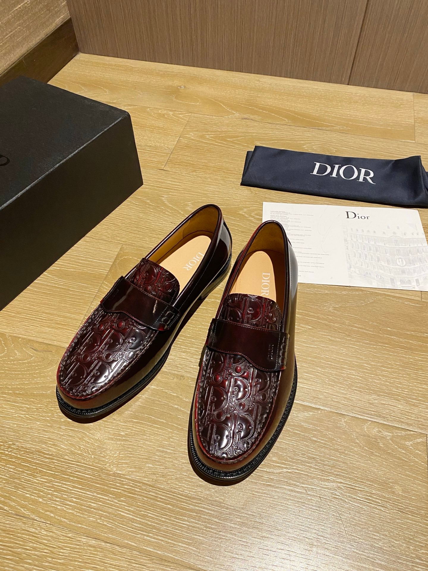 Dark red leather loafers with glossy finish, strap detail, and stitched edges