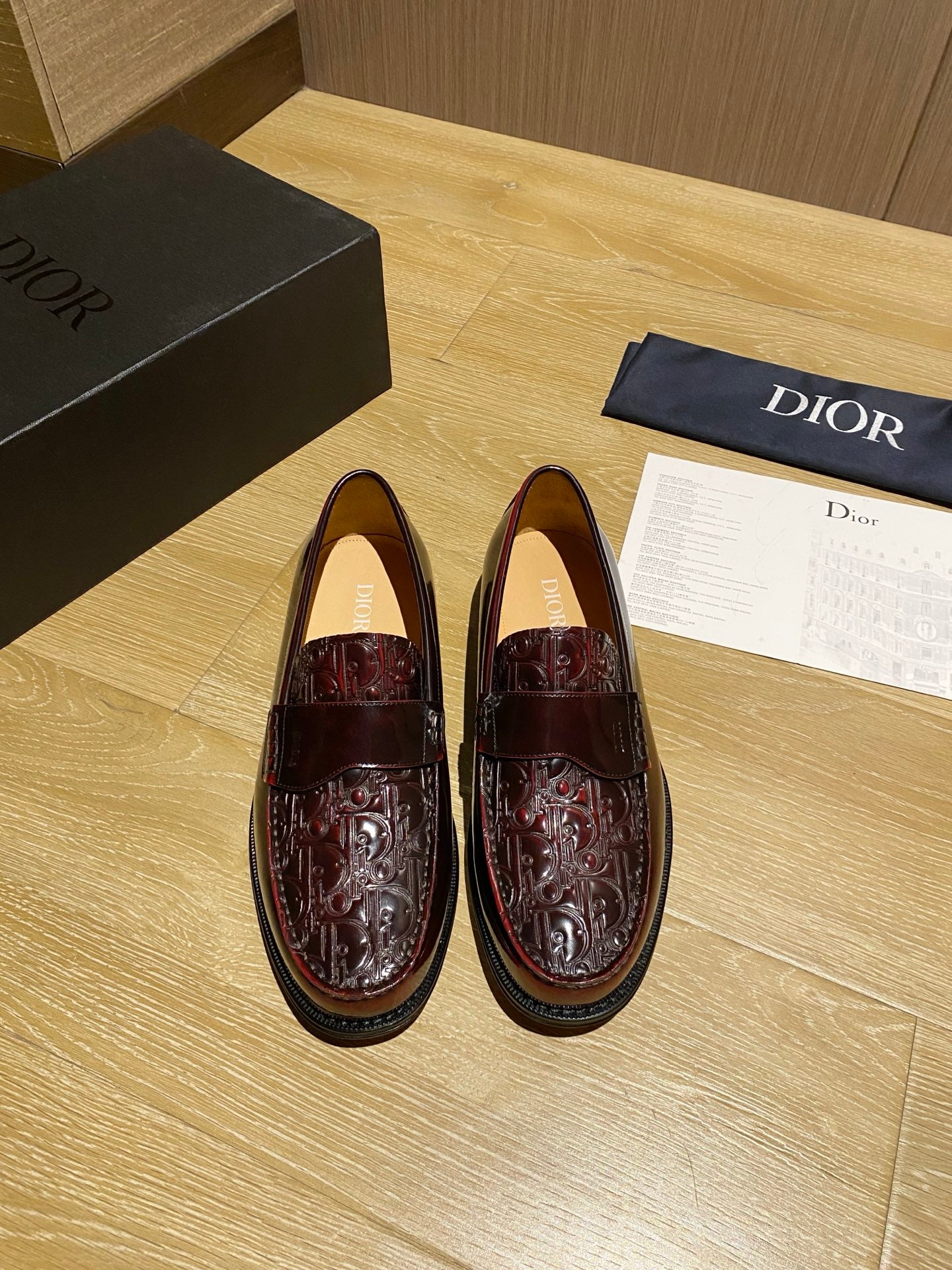 Burgundy leather unisex loafers with embossed pattern and strap detail