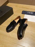Black leather loafers with decorative top strap and glossy embossed finish