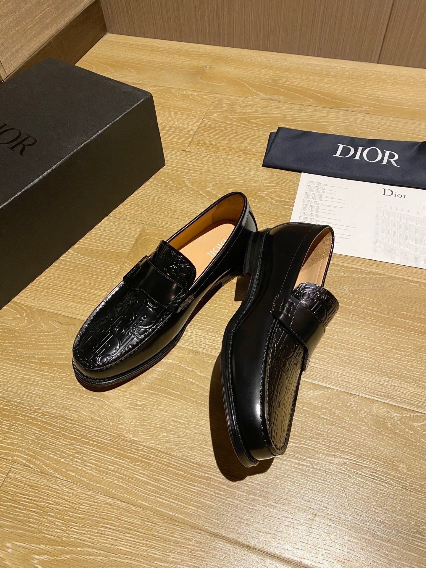 Black leather loafers with decorative top strap and glossy embossed finish